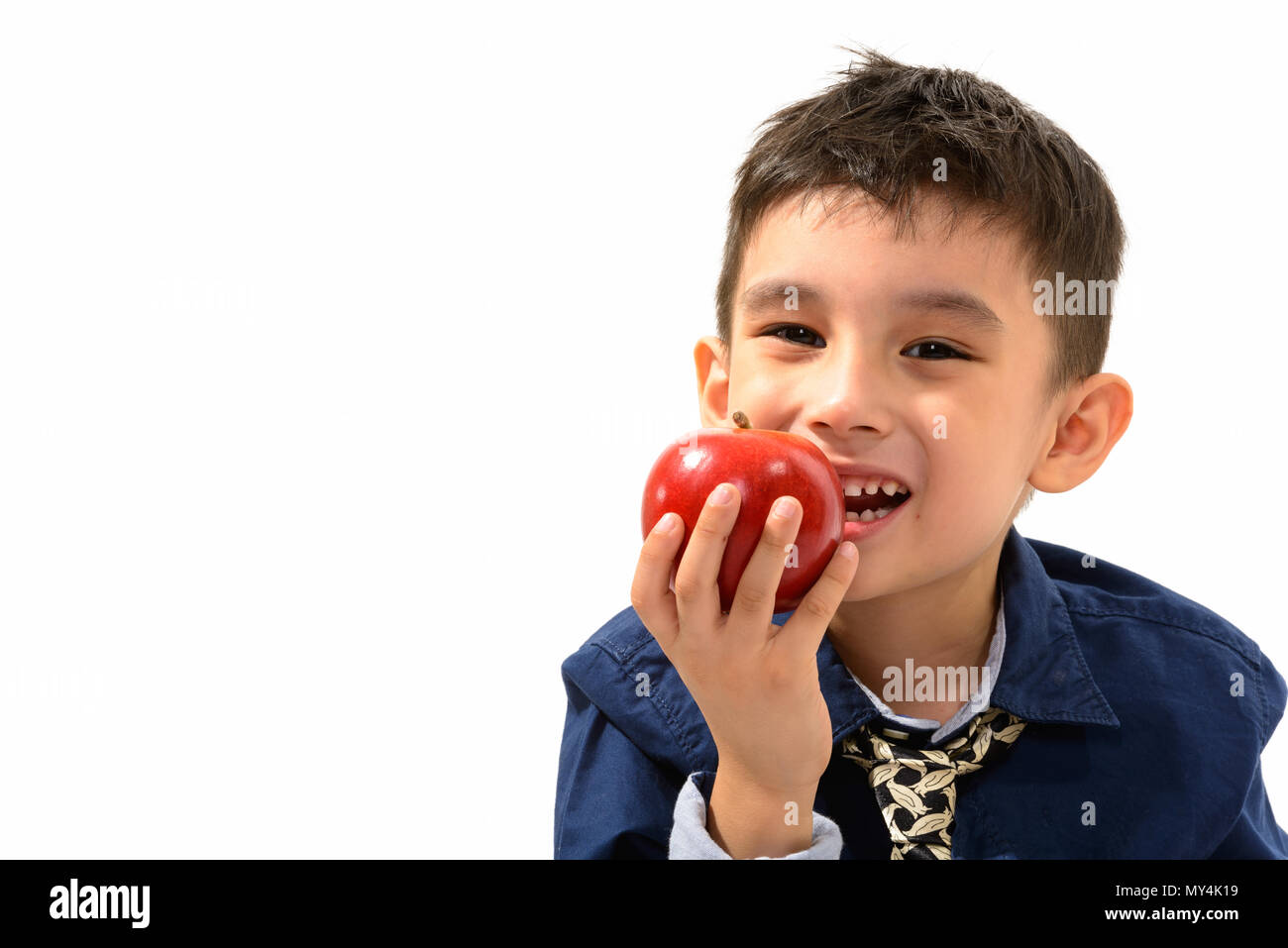 Studio shot of cute happy boy smiling and eating apple Stock Photo