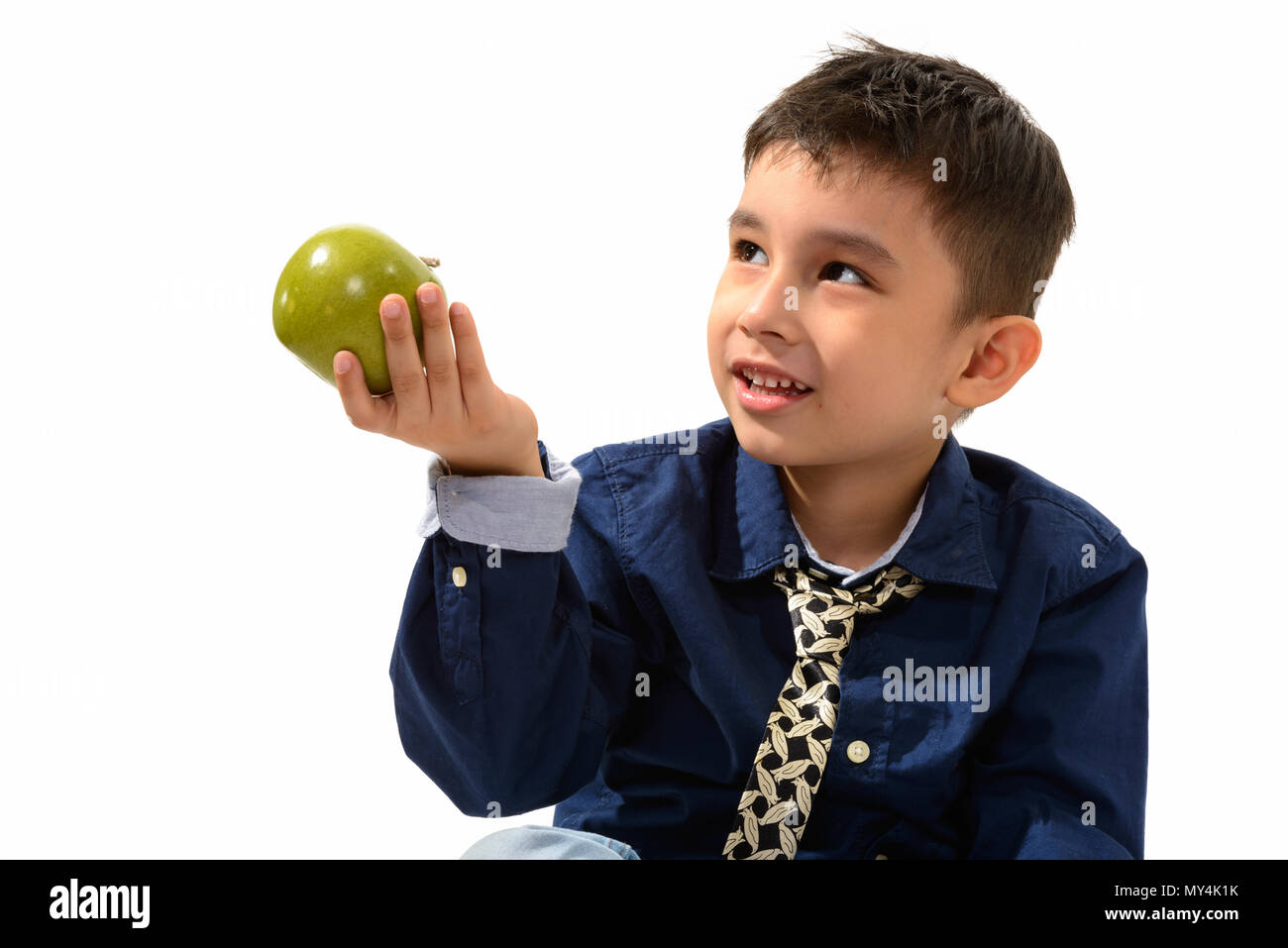 Studio shot of cute happy boy smiling and giving green apple whi Stock Photo