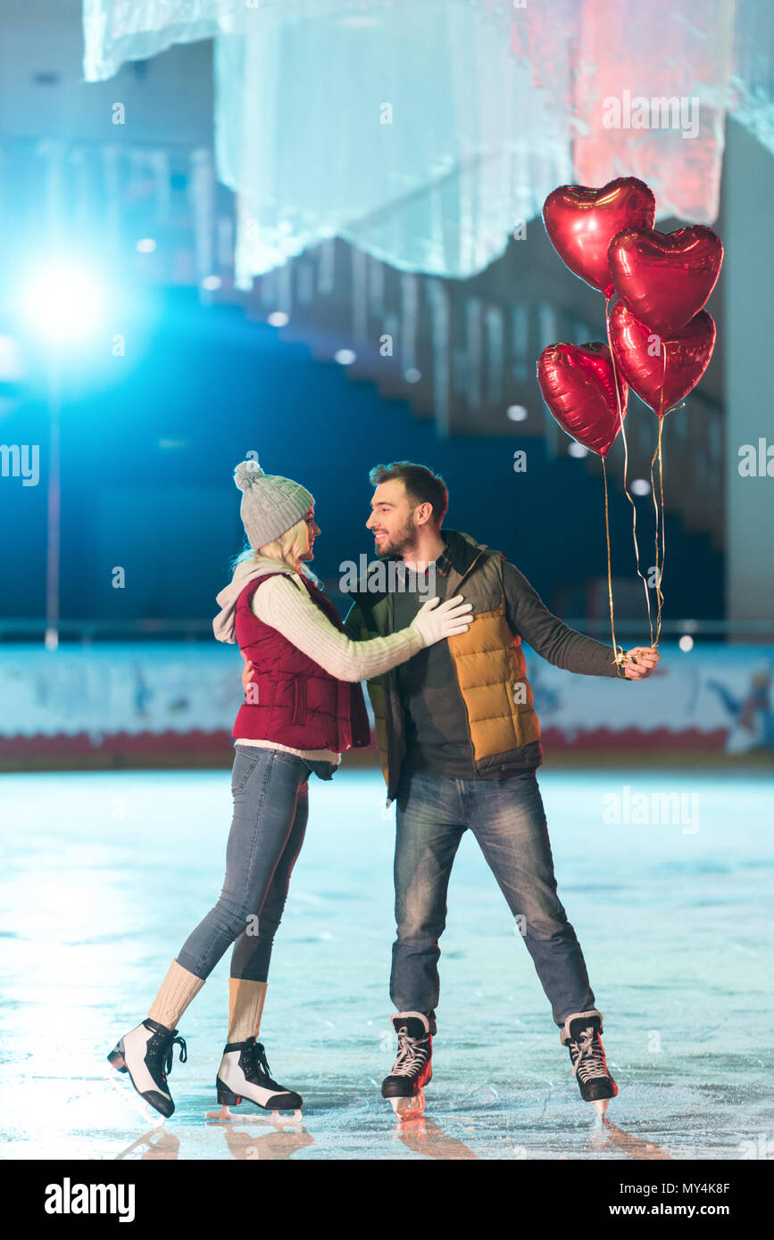 beautiful happy young couple with heart shaped balloons smiling each ...