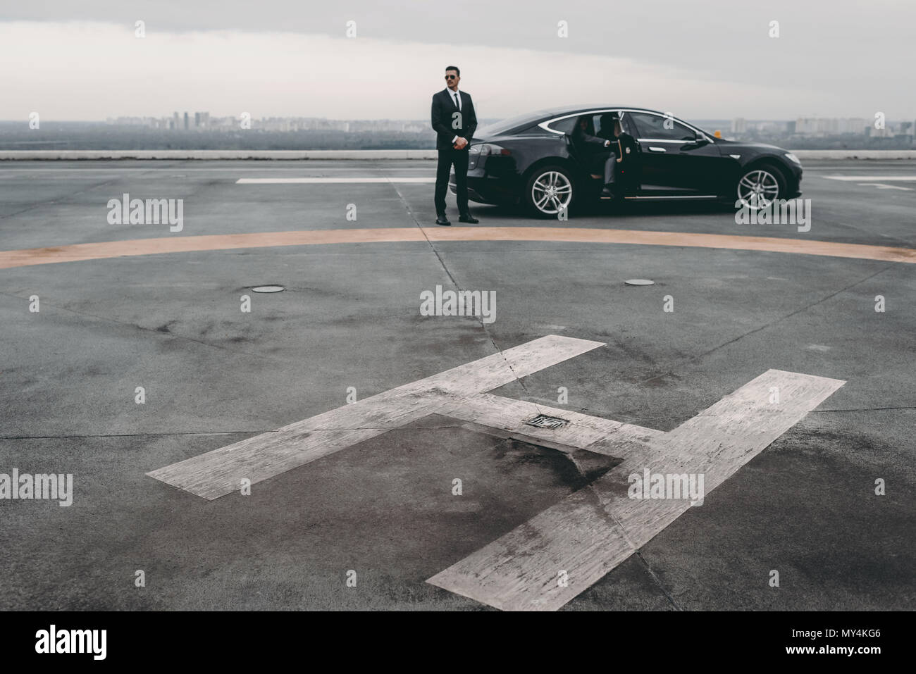 bodyguard standing close to businessman car on helipad Stock Photo