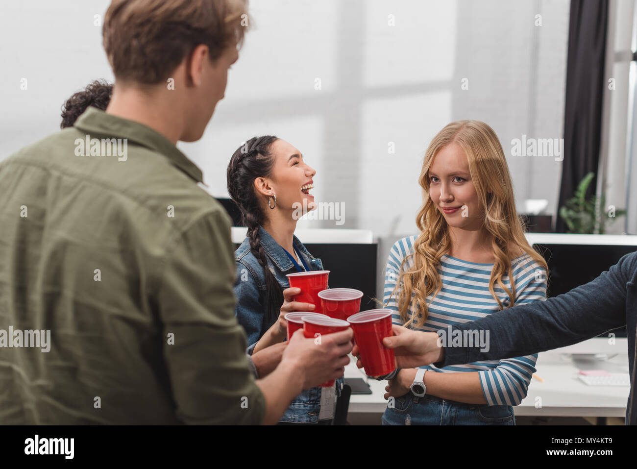 young attractive people clinking cups at modern office Stock Photo - Alamy