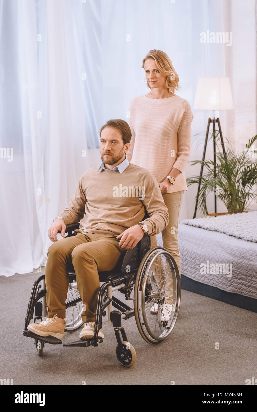 husband on wheelchair and wife looking away in bedroom Stock Photo - Alamy