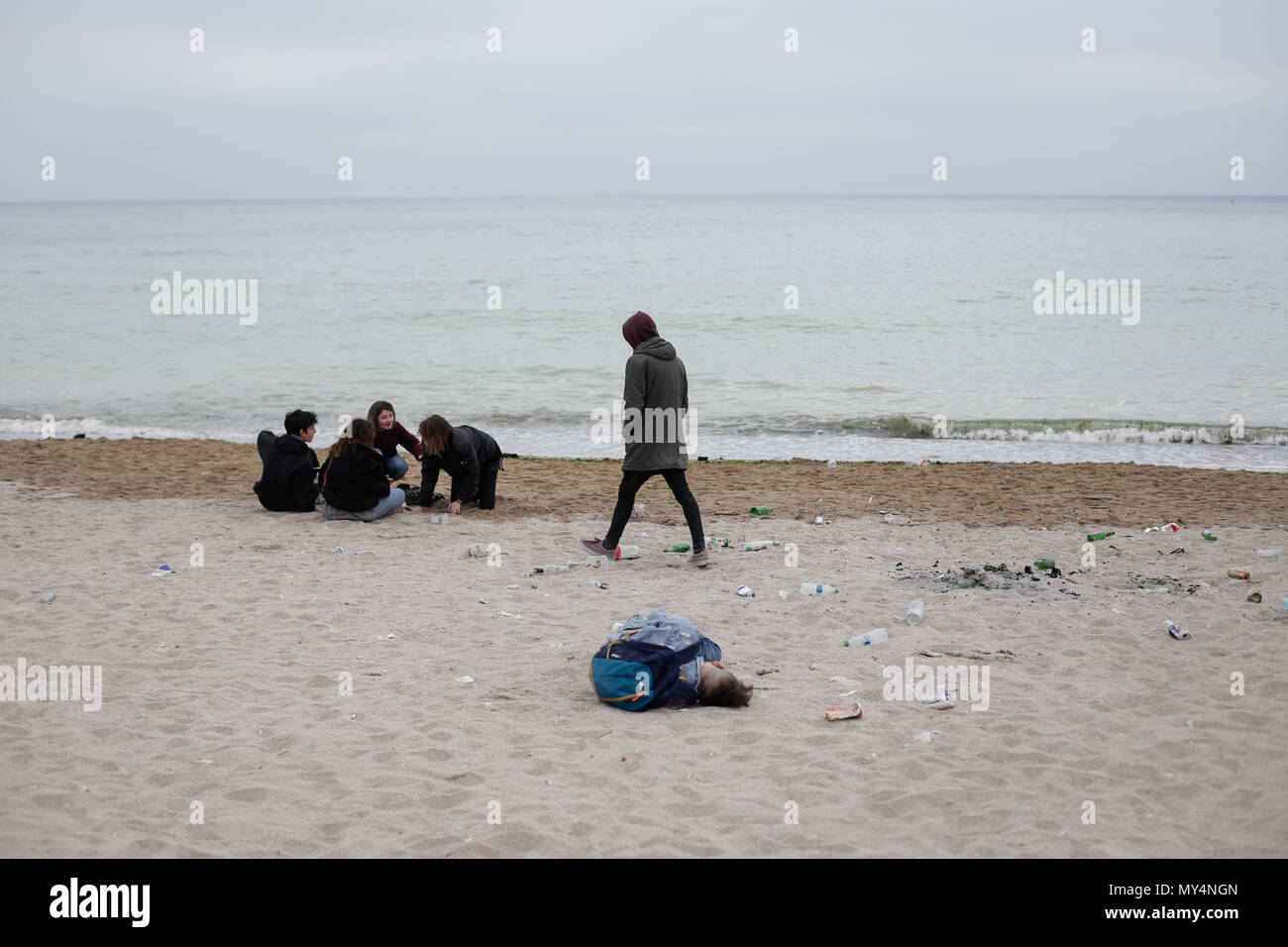 VAMA VECHE, ROMANIA - MAY 1, 2018: Young people rest on the beach amongst debris (especially empty bottles), after partying all night, early in the mo Stock Photo