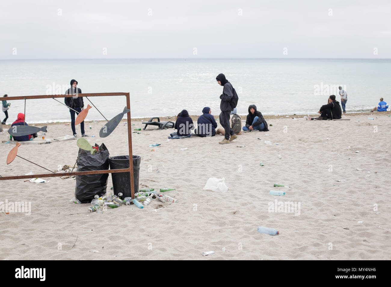 VAMA VECHE, ROMANIA - MAY 1, 2018: Young people rest on the beach amongst debris (especially empty bottles), after partying all night, early in the mo Stock Photo