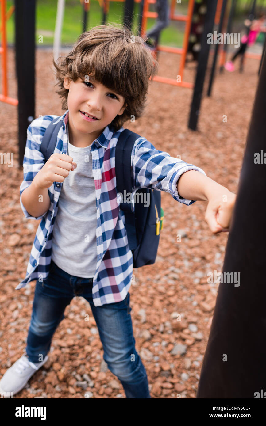 little boy hitting punching bag and looking at camera on playground