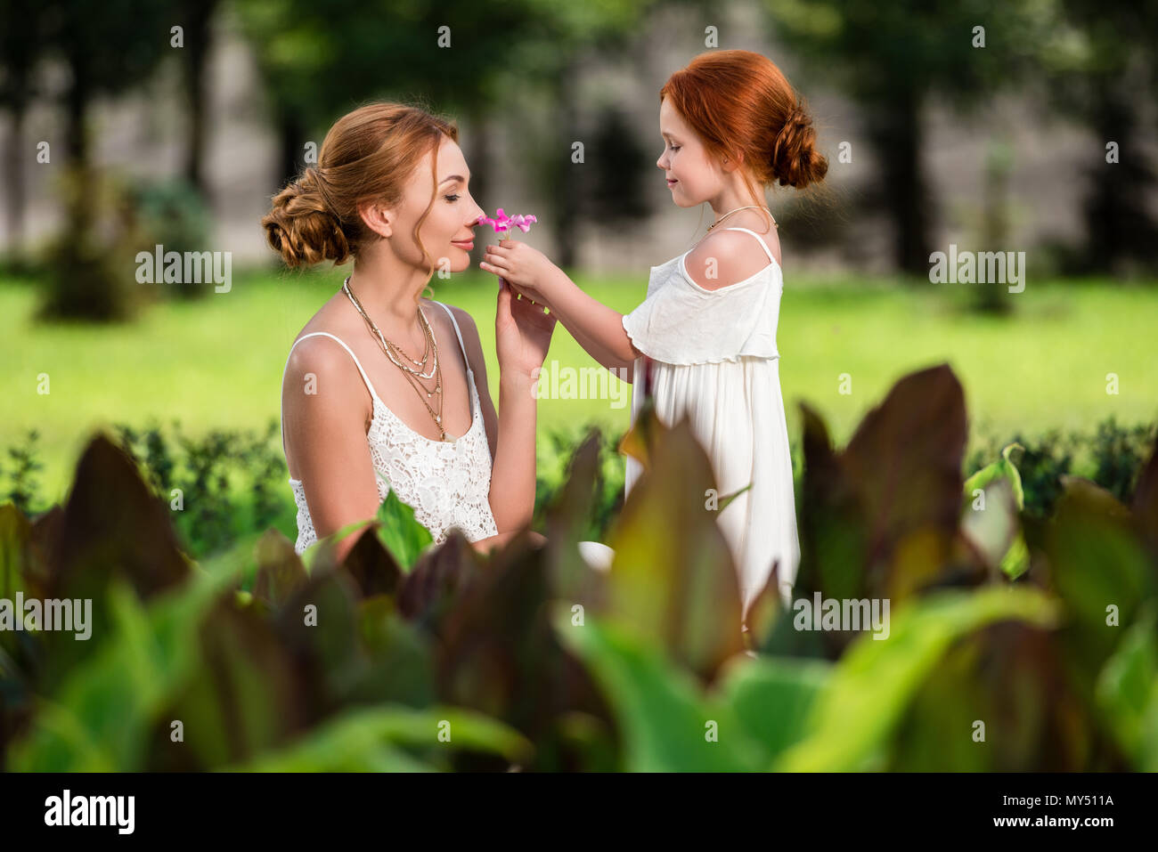 side view of beautiful happy mother and daughter in white dresses