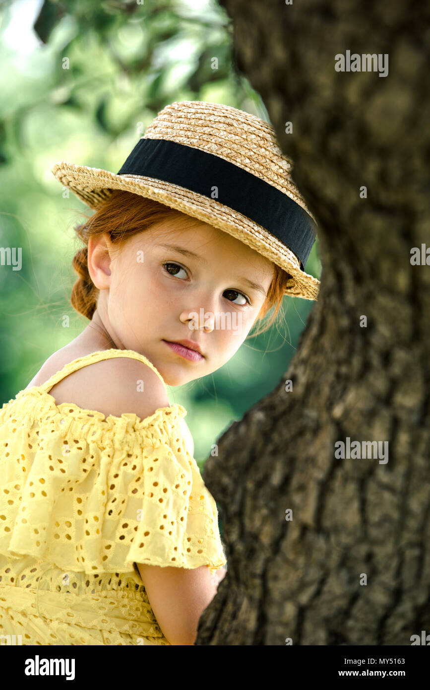portrait of beautiful pensive little girl in straw hat looking away in ...