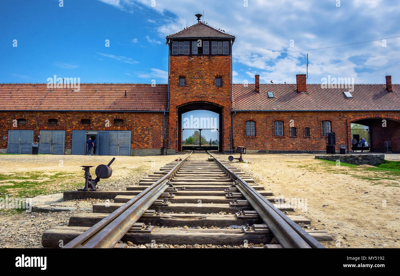 Main gate to nazi concentration camp of Auschwitz Birkenau with train rail, Poland Stock Photo