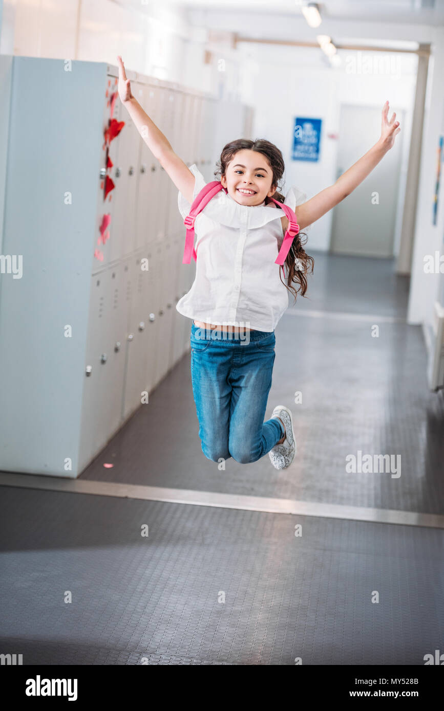 happy girl jumping in school corridor with raised hands Stock Photo - Alamy