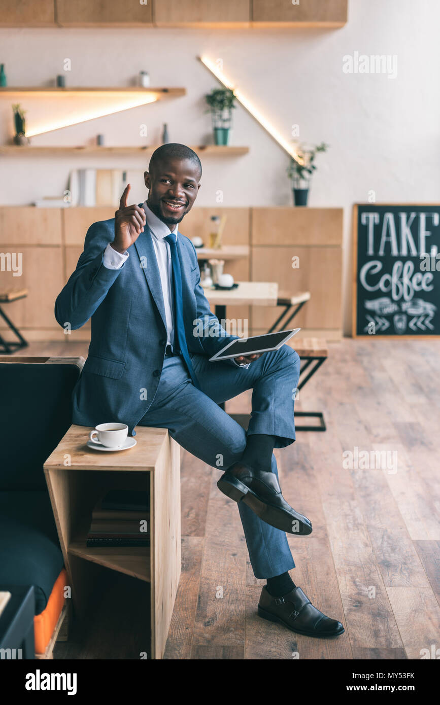 handsome african american businessman having idea and using digital tablet during coffee break in cafe Stock Photo