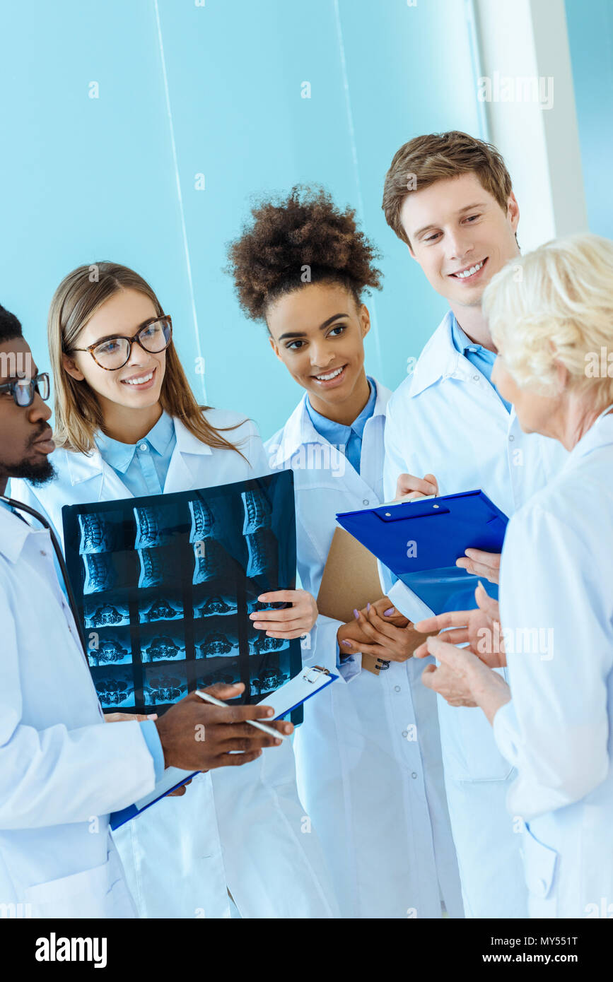 A multiracial group of young medical interns listening to a elder doctor in a hospital corridor Stock Photo