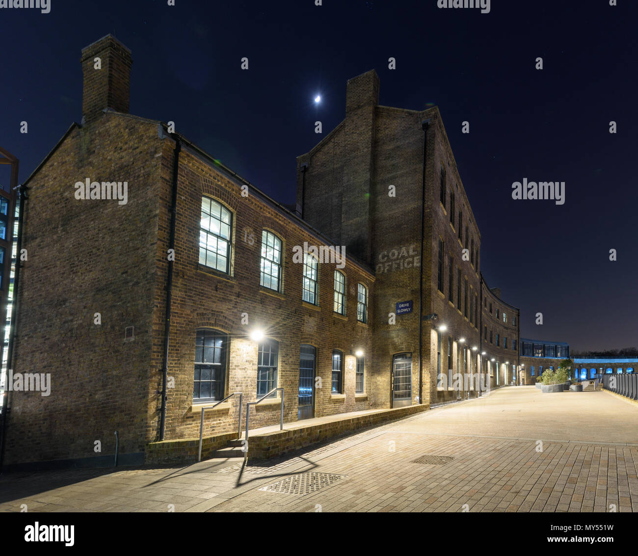 London, England, UK - February 22, 2018: A half moon hangs in the night sky over the Coal Office, part of the King's Cross urban regeneration project  Stock Photo