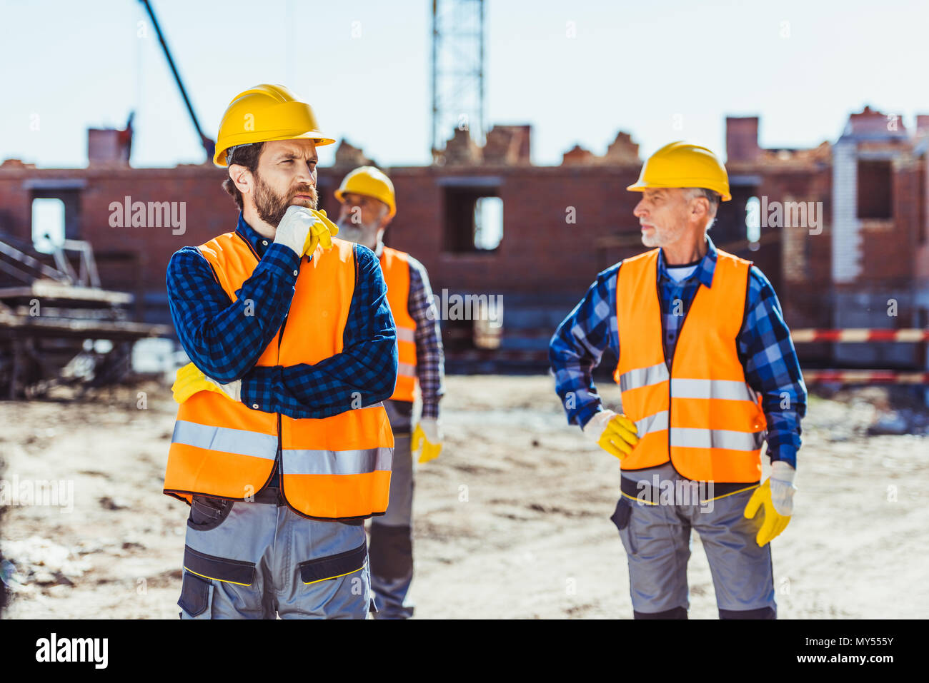Construction workers in uniform standing outside, examining the