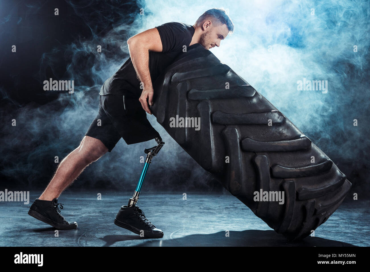 side view of strong sportsman with leg prosthesis pulling tire Stock ...