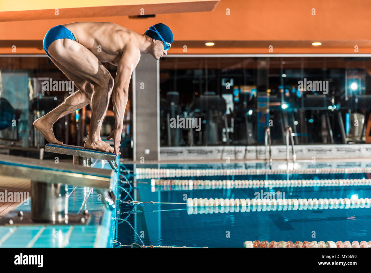 swimmer standing on diving board ready to jump into competition