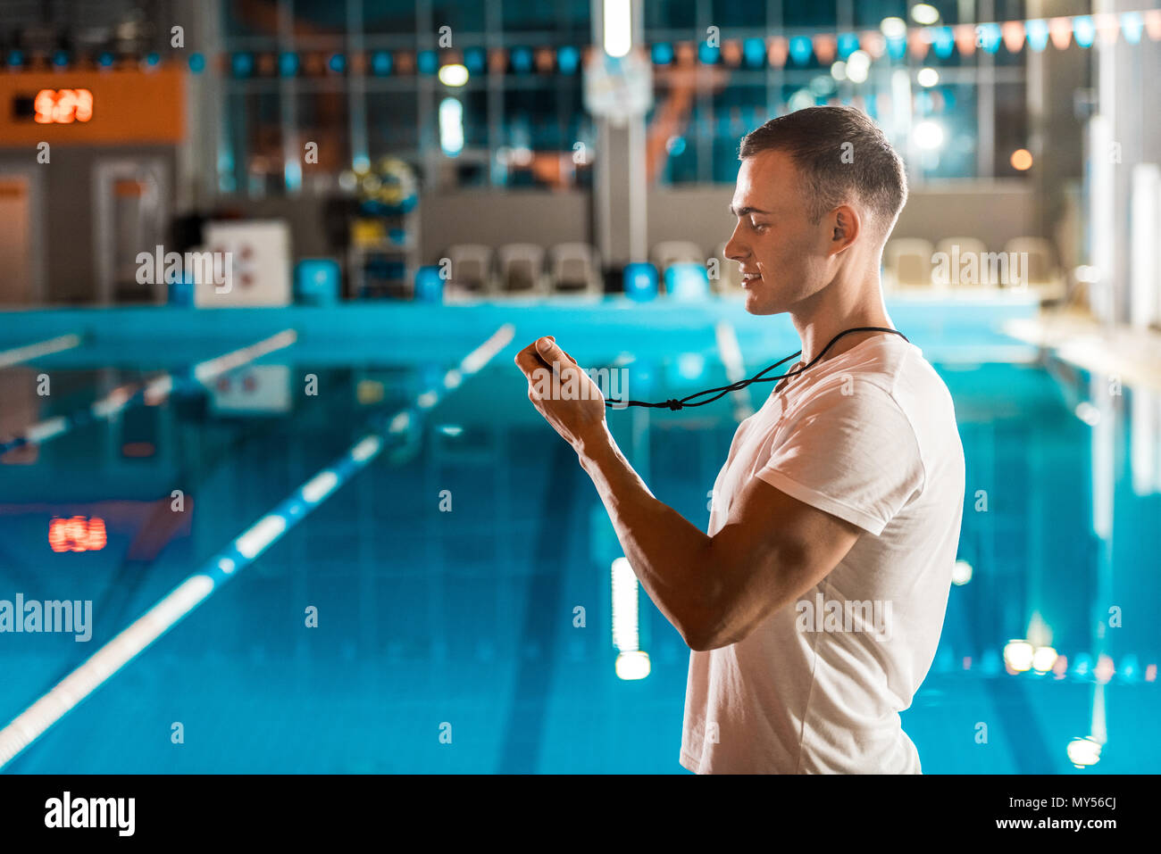 handsome swim coach with stopwatch at competition swimming pool Stock