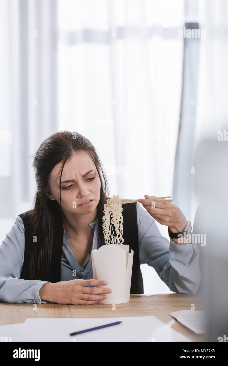 disgusted overworked manageress with box of junk take away noodles at workplace Stock Photo
