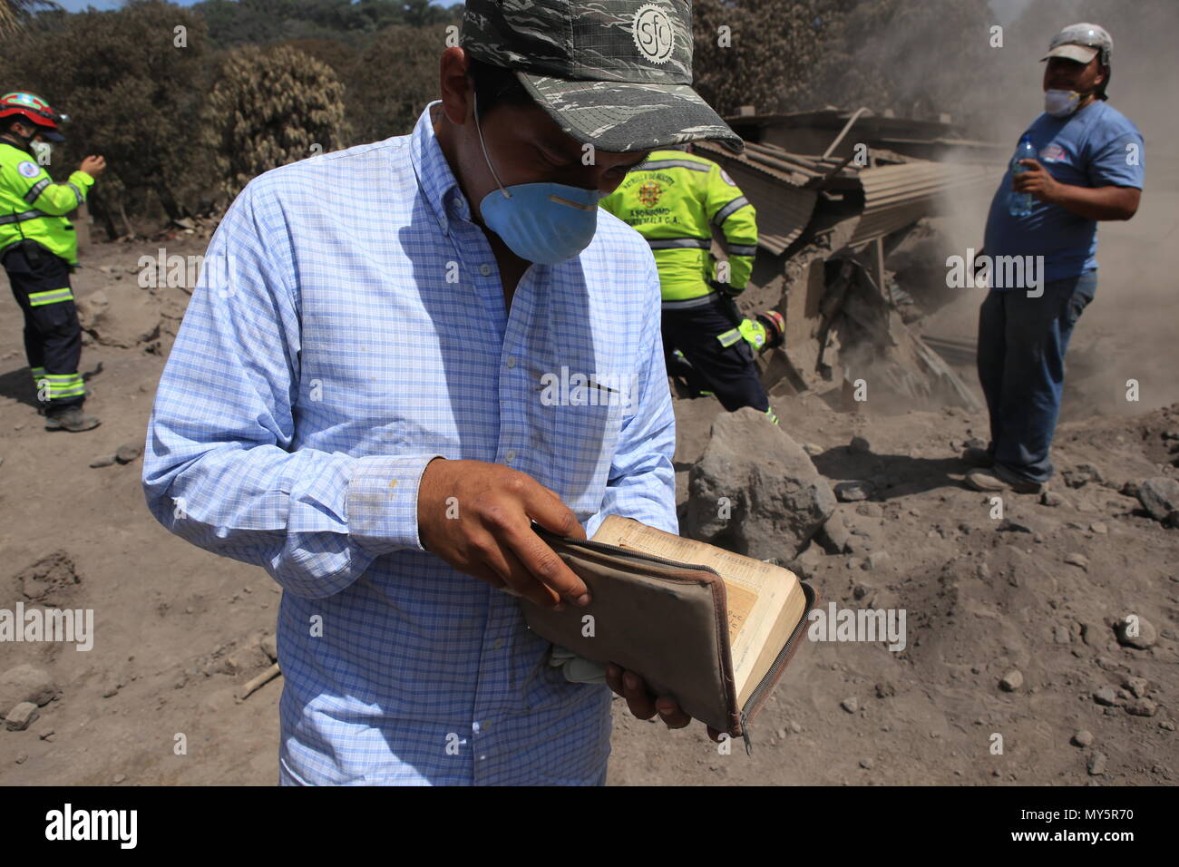 06 June 2018, Guatemala, San Miguel Los Lotes: Axel Toma, the only survivor  from his family, finding a bible which was buried under the ash after the  eruption of a volcano. The