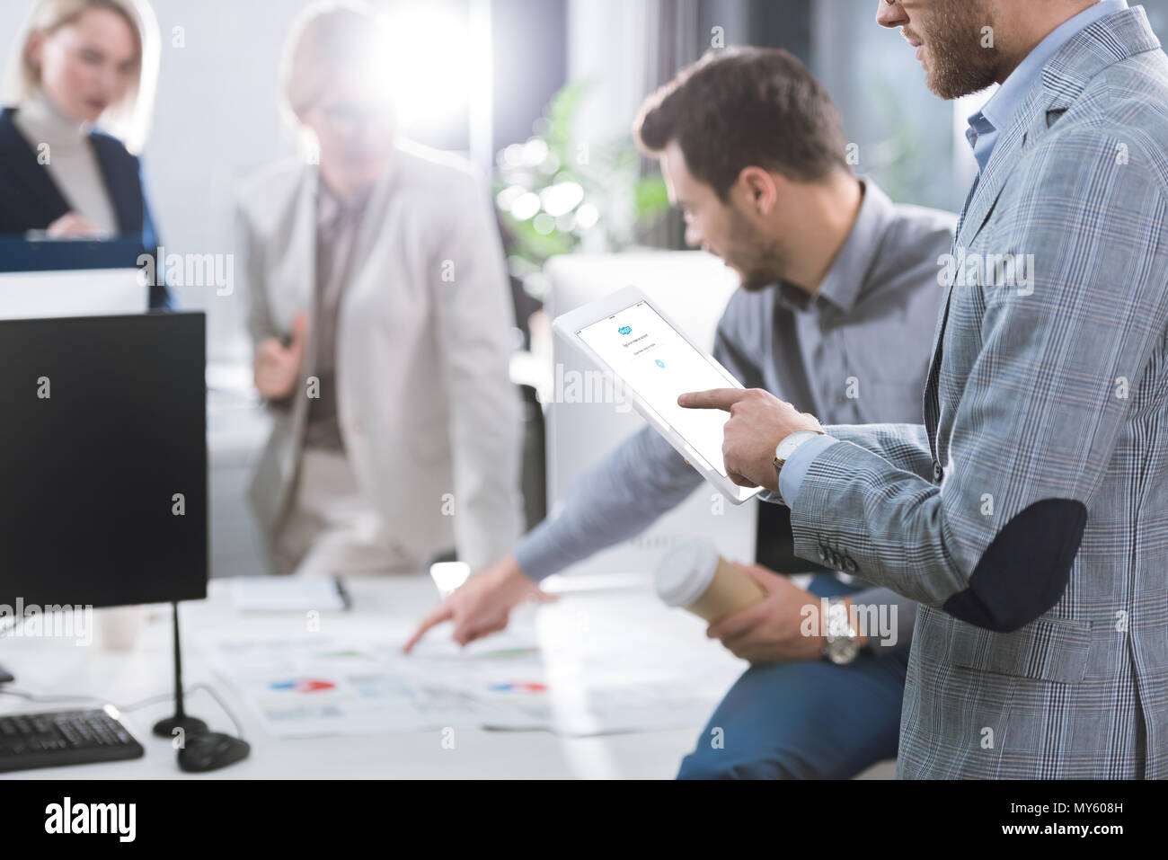 selective focus of businessman using digital tablet with skype logo on screen in office Stock Photo