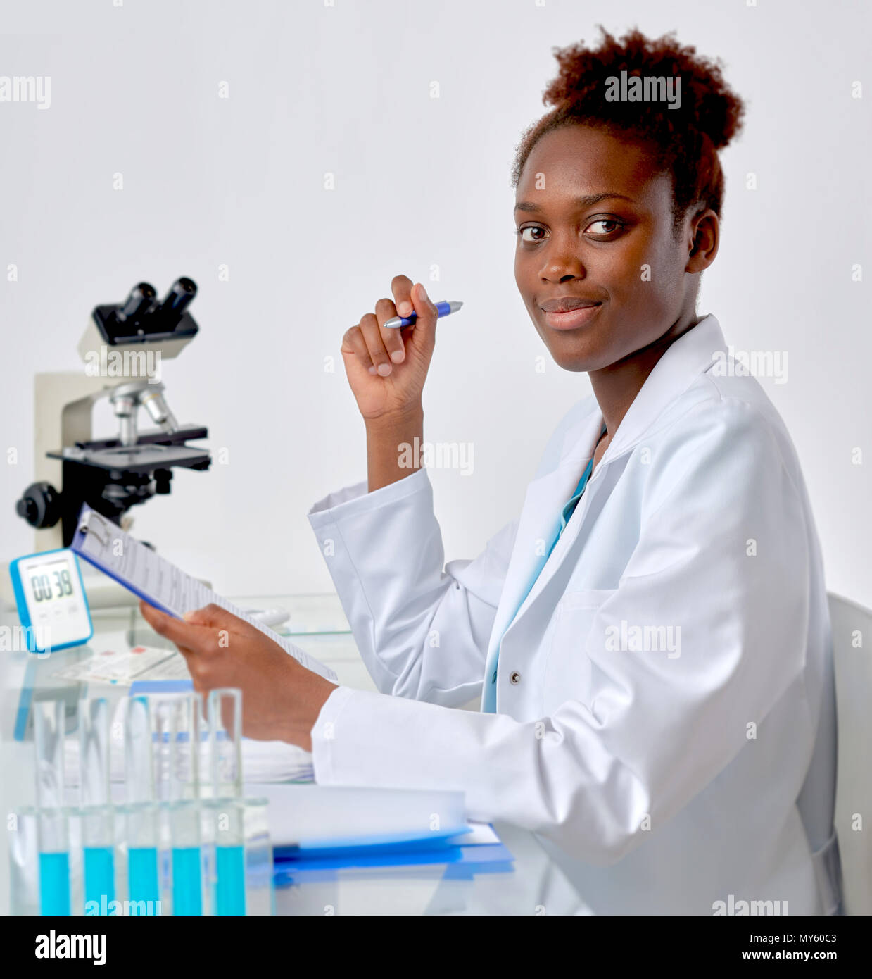 African scientist, medical or or graduate student. Bright, confident young woman in lab coat inerrupted her work to look at the viewer. Stock Photo