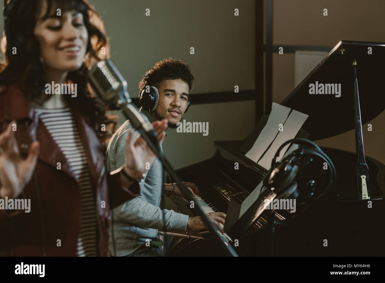 young handsome piano player looking at singer performing song Stock Photo