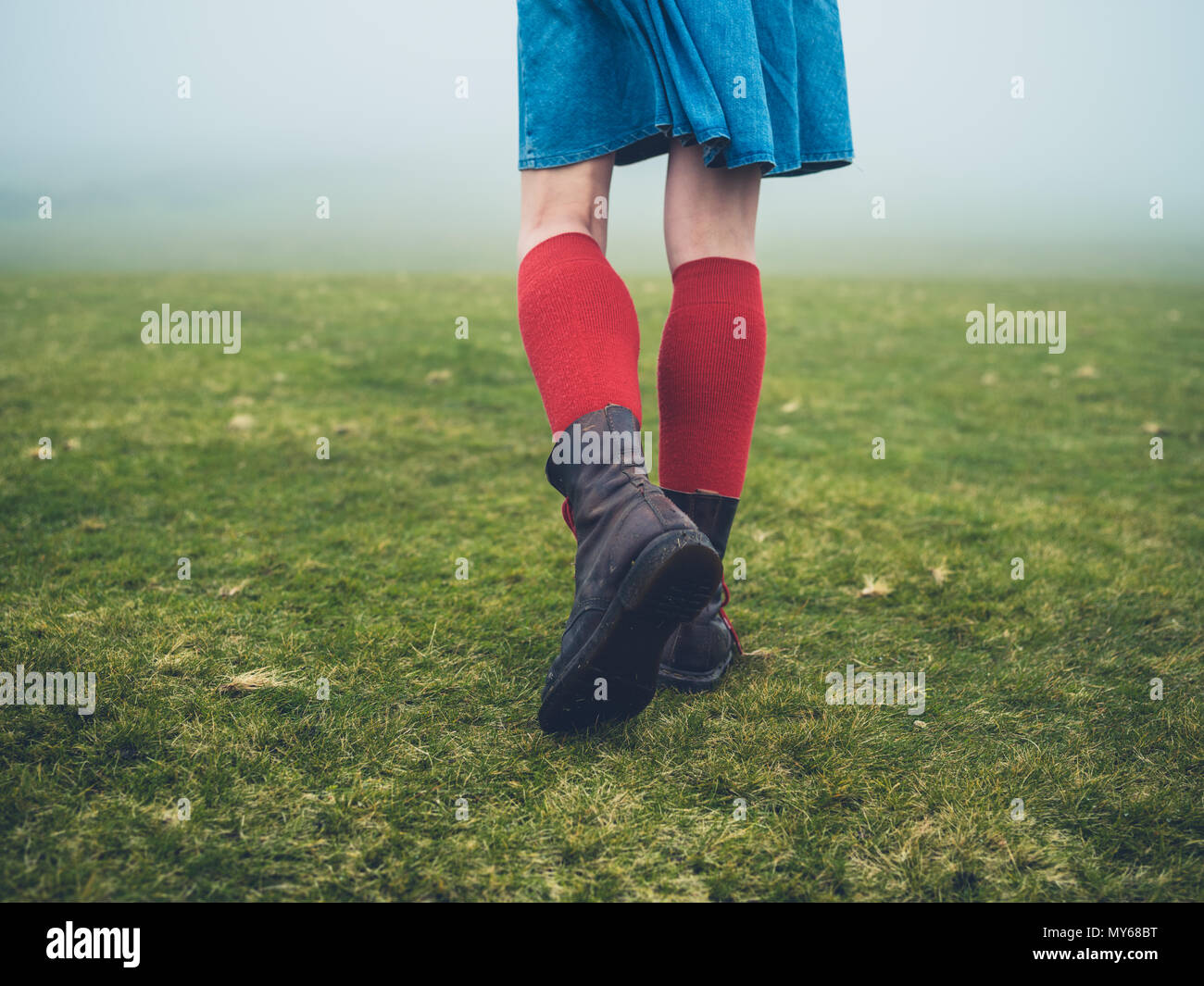 A young woman wearing hiking boots and socks is walking on the moor in
