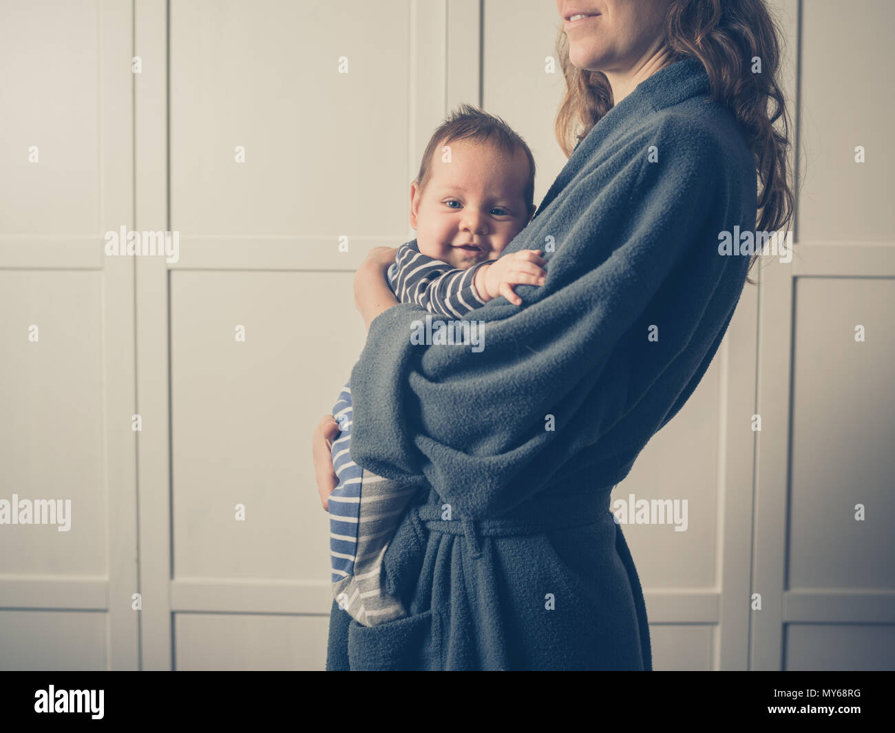 A young mother wearing a bathrobe is holding her baby Stock Photo Alamy