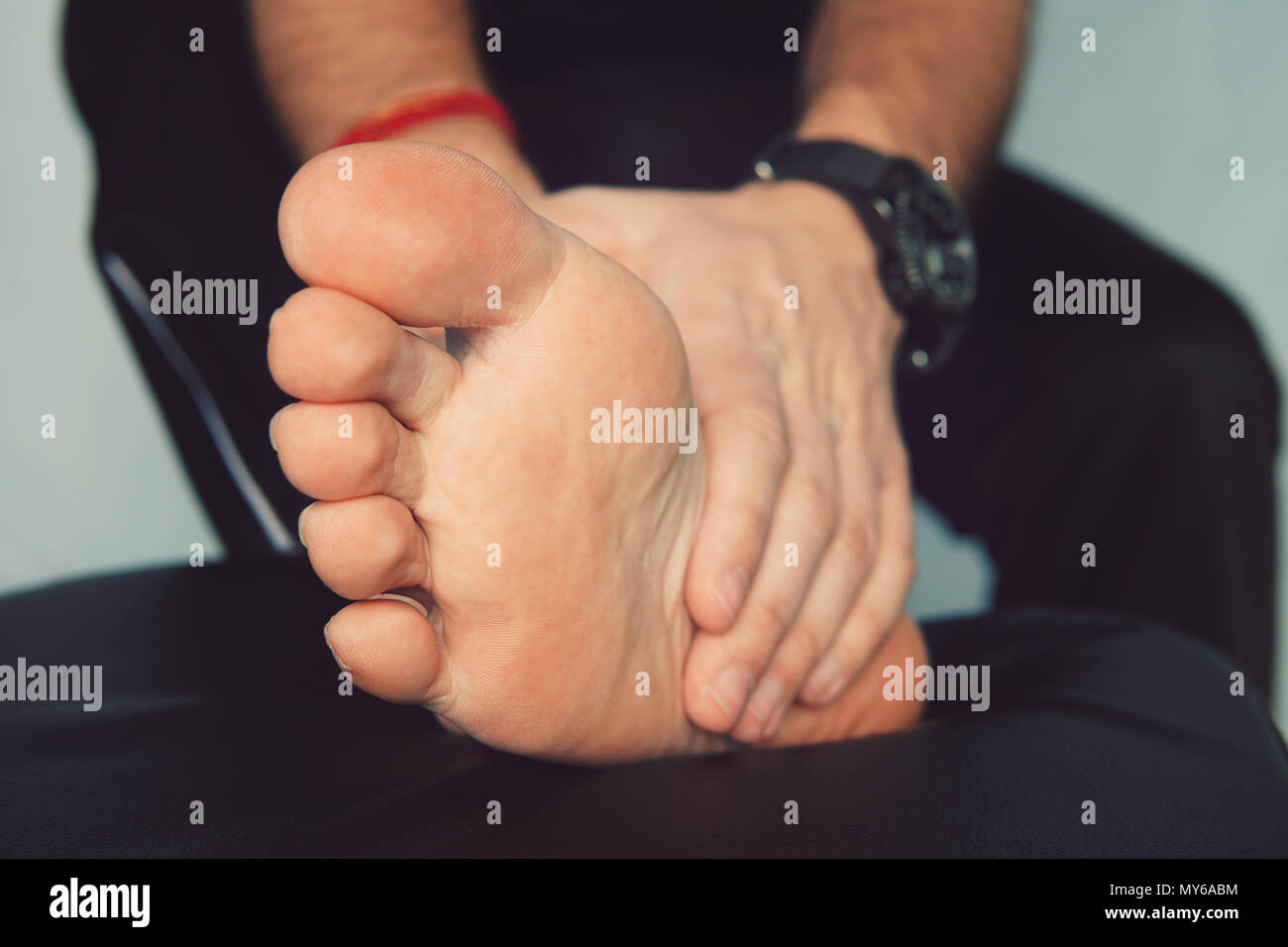 Man's hand being massaged a foot. Man with painful and inflamed gout on his foot around the big toe area. Stock Photo