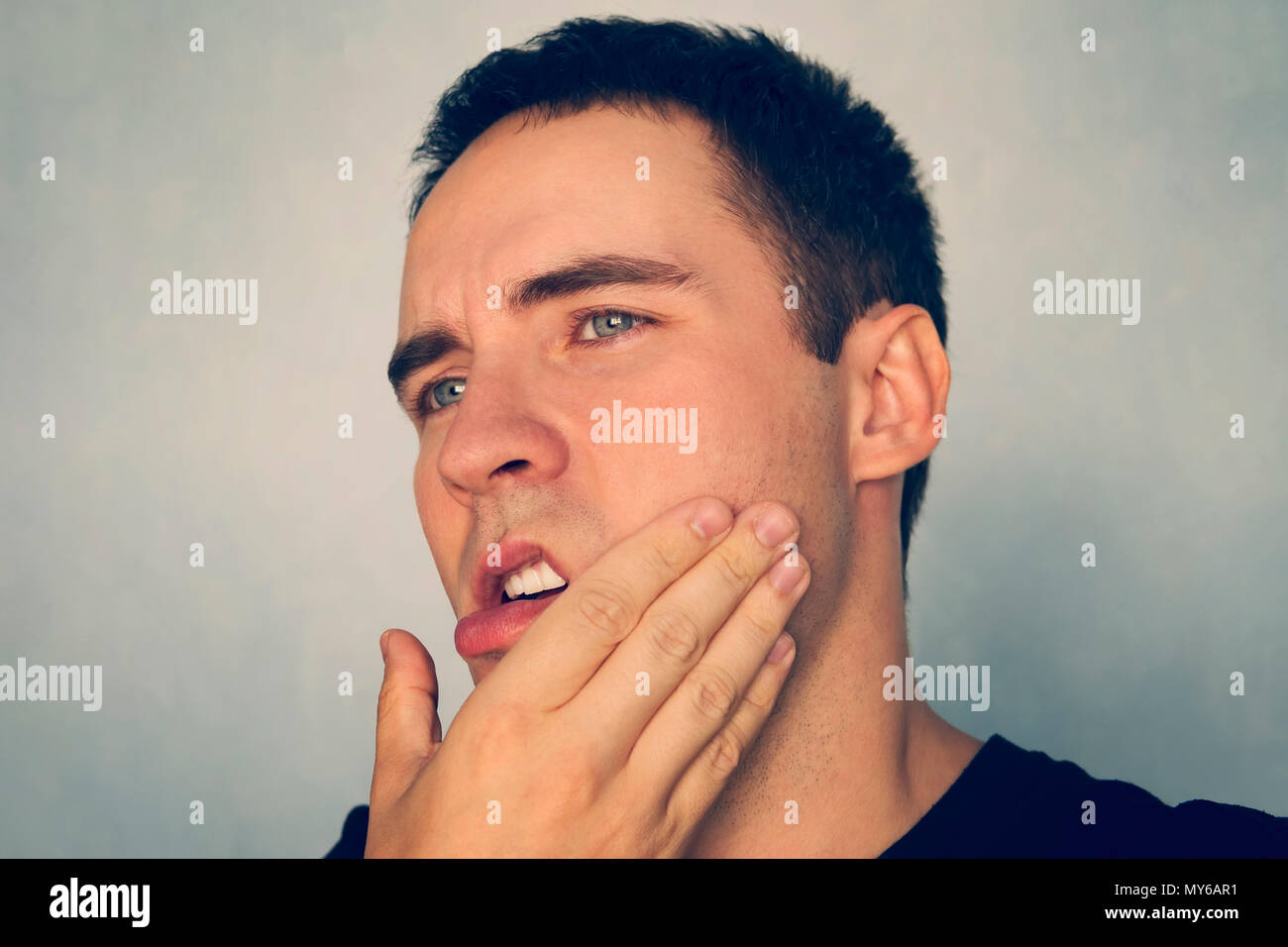 Dramatic Shot of a Man in Pain holding his Jaw. Toothache . A punch in