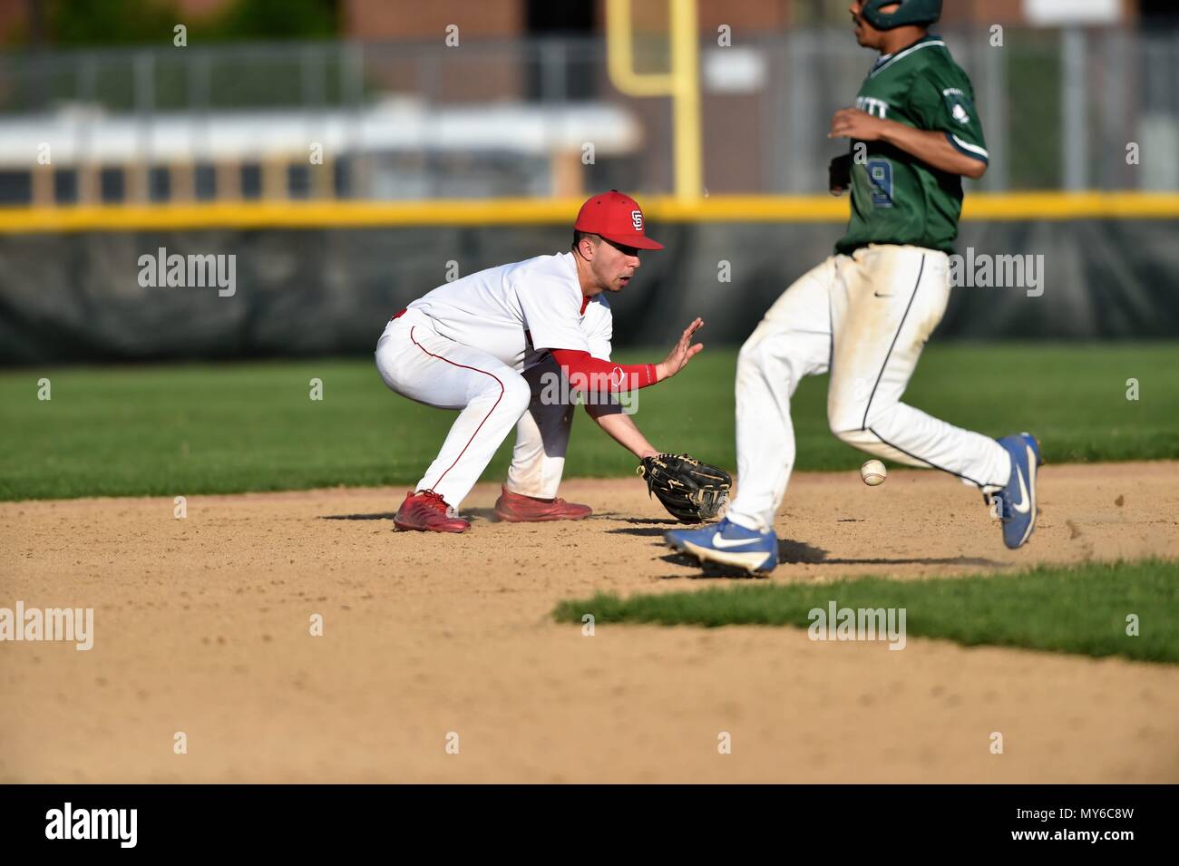 Second baseman fielding a ground ball as an opposing base runner advanced to second base. USA. Stock Photo