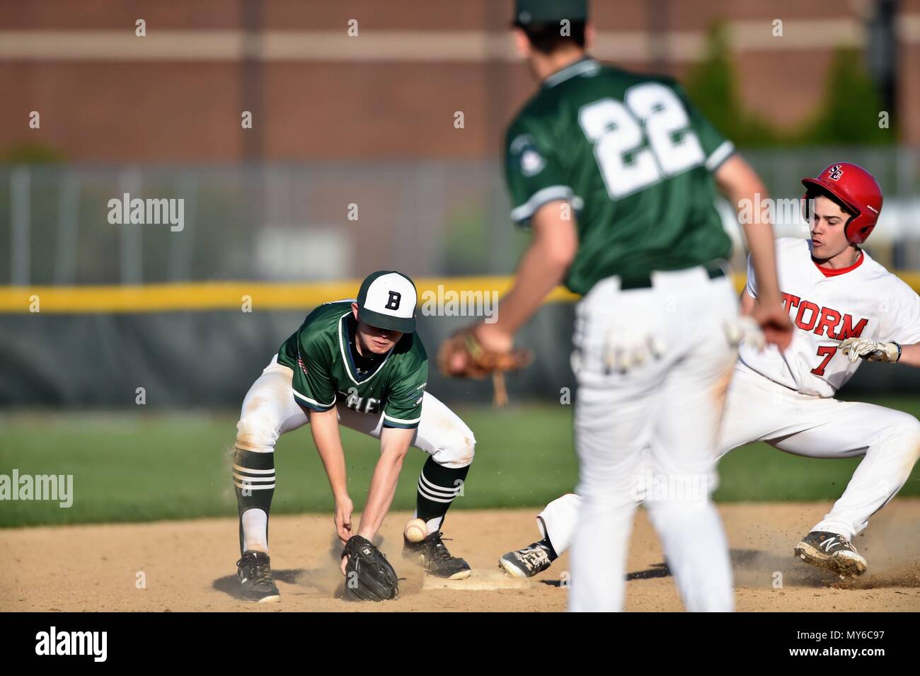 Second baseman fielding a low throw at second base allowing the runner to arrive safely at the bag standing up. USA. Stock Photo