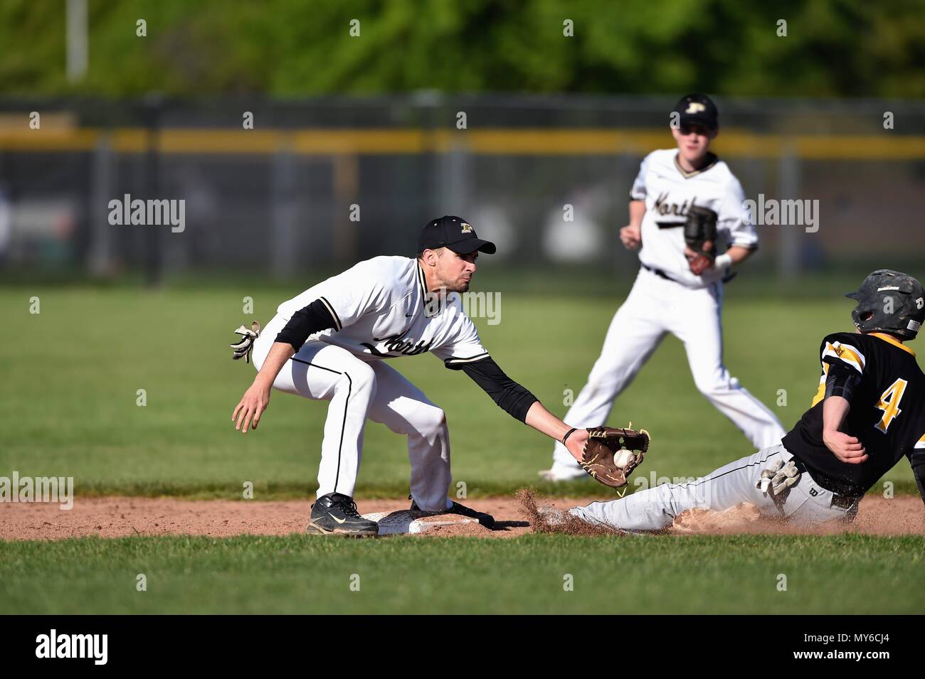 Middle infielder accepting a late throw from the catcher as an opposing runners slides into second base on a stolen base attempt. USA. Stock Photo