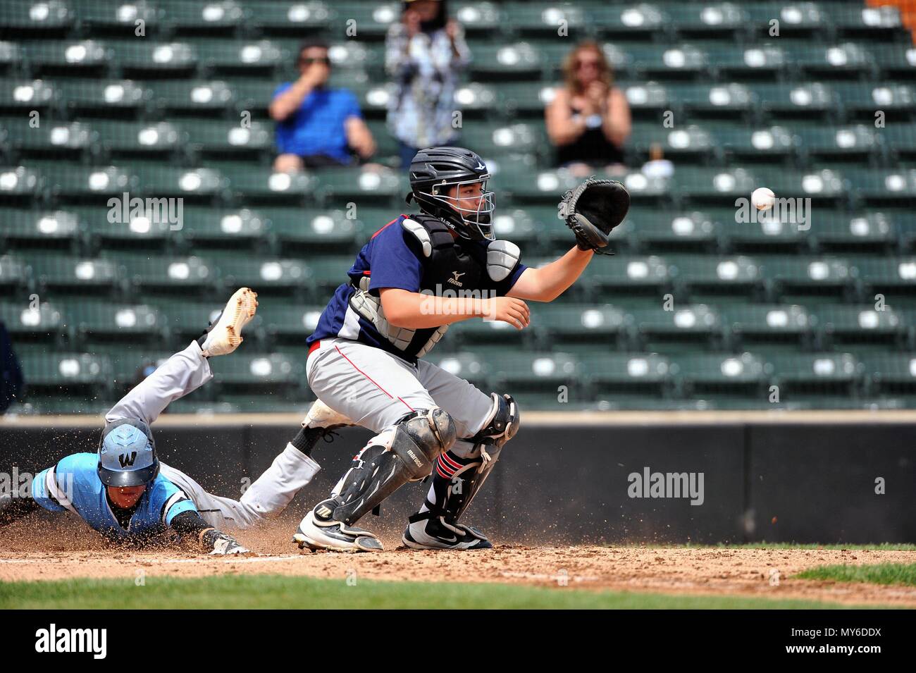 Runner scoring as the opposing catcher awaits a tardy throw from the