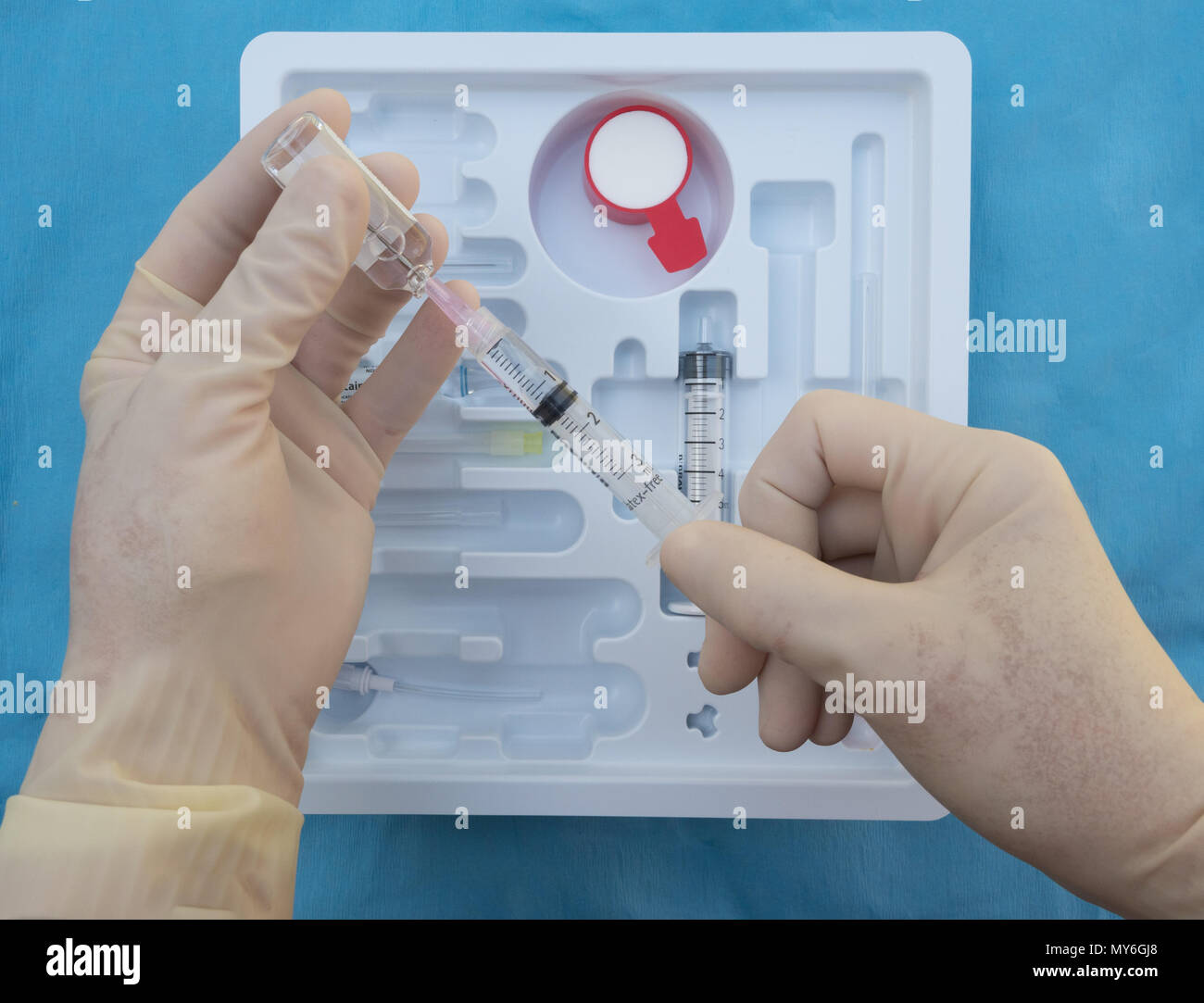 A right handed anesthesiologist withdrawing lidocaine or novocaine into