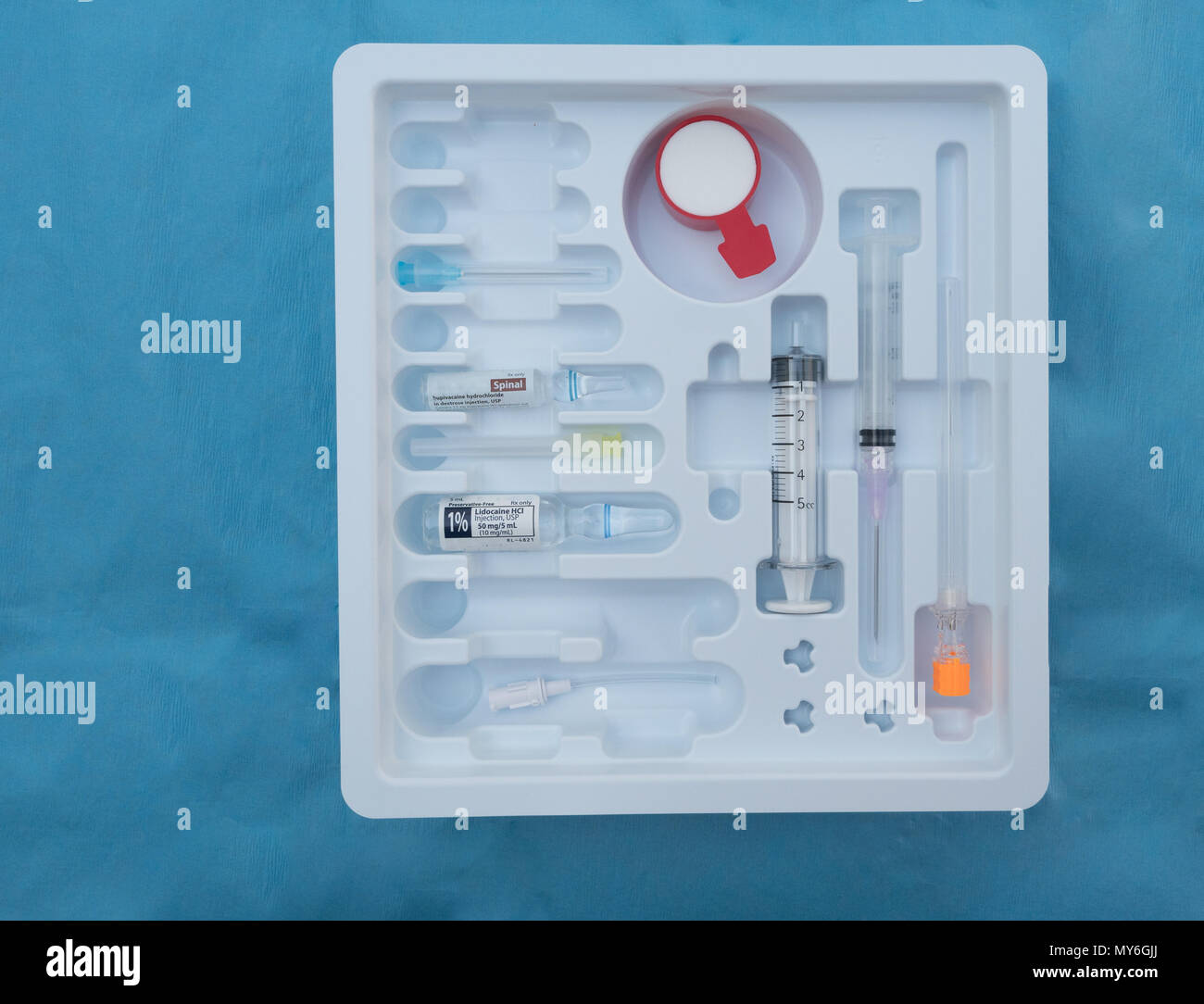A sterile spinal tray with needles, syringes and ampules of medication