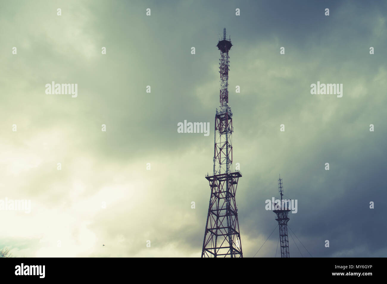 Radio telecommunications tower, Mobile phone tower and old steel pipe in storm clouds. dramatic landscape with cloud storm cloud and metal TV tower Stock Photo