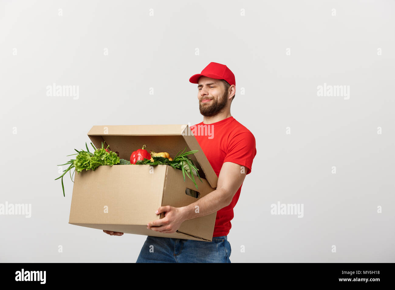 Delivery Concept Handsome delivery man is holding a heavy grocery box