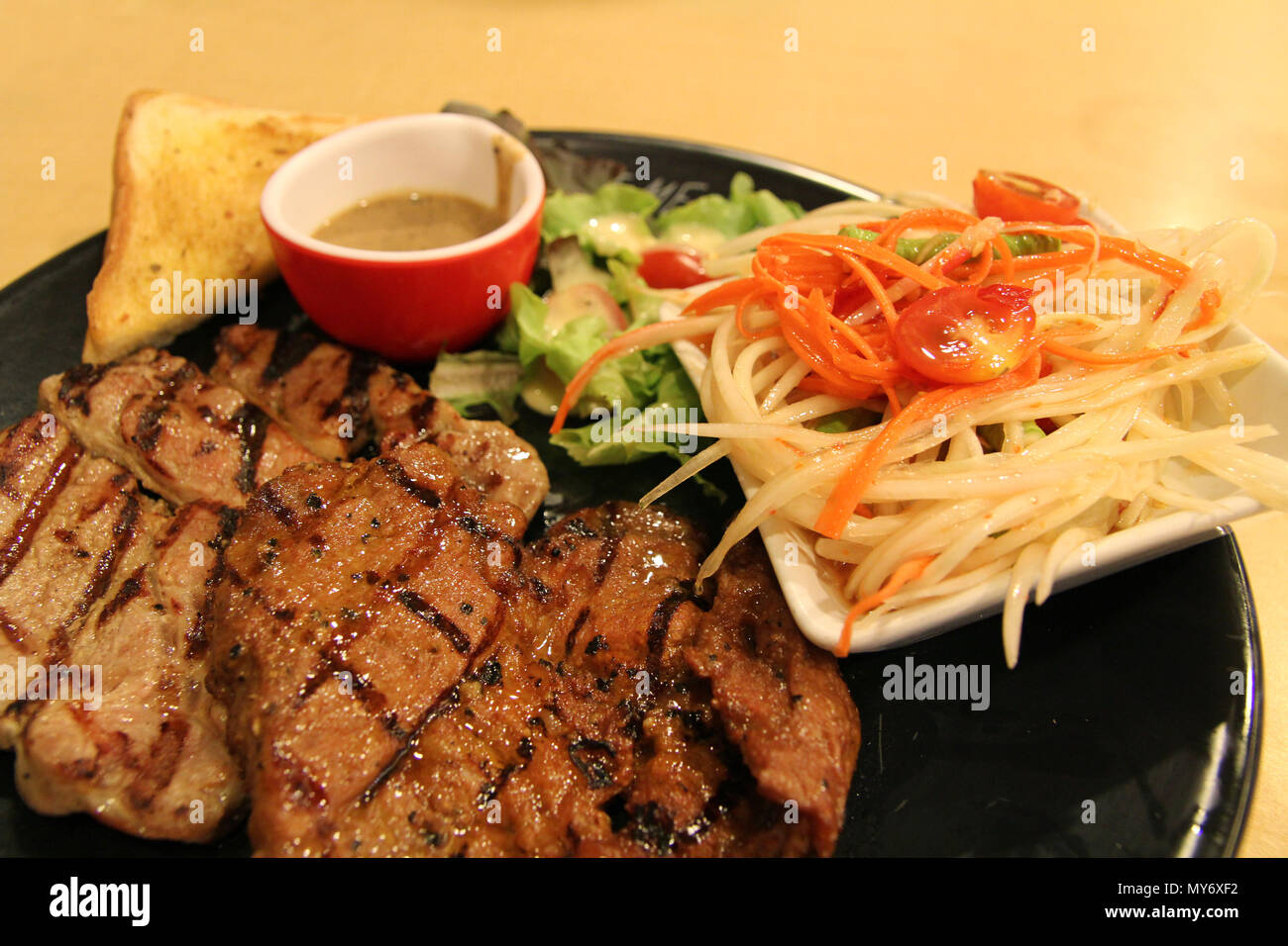 Grilled pork chop and steak with salad, papaya salad, bread and sauce Stock Photo Alamy