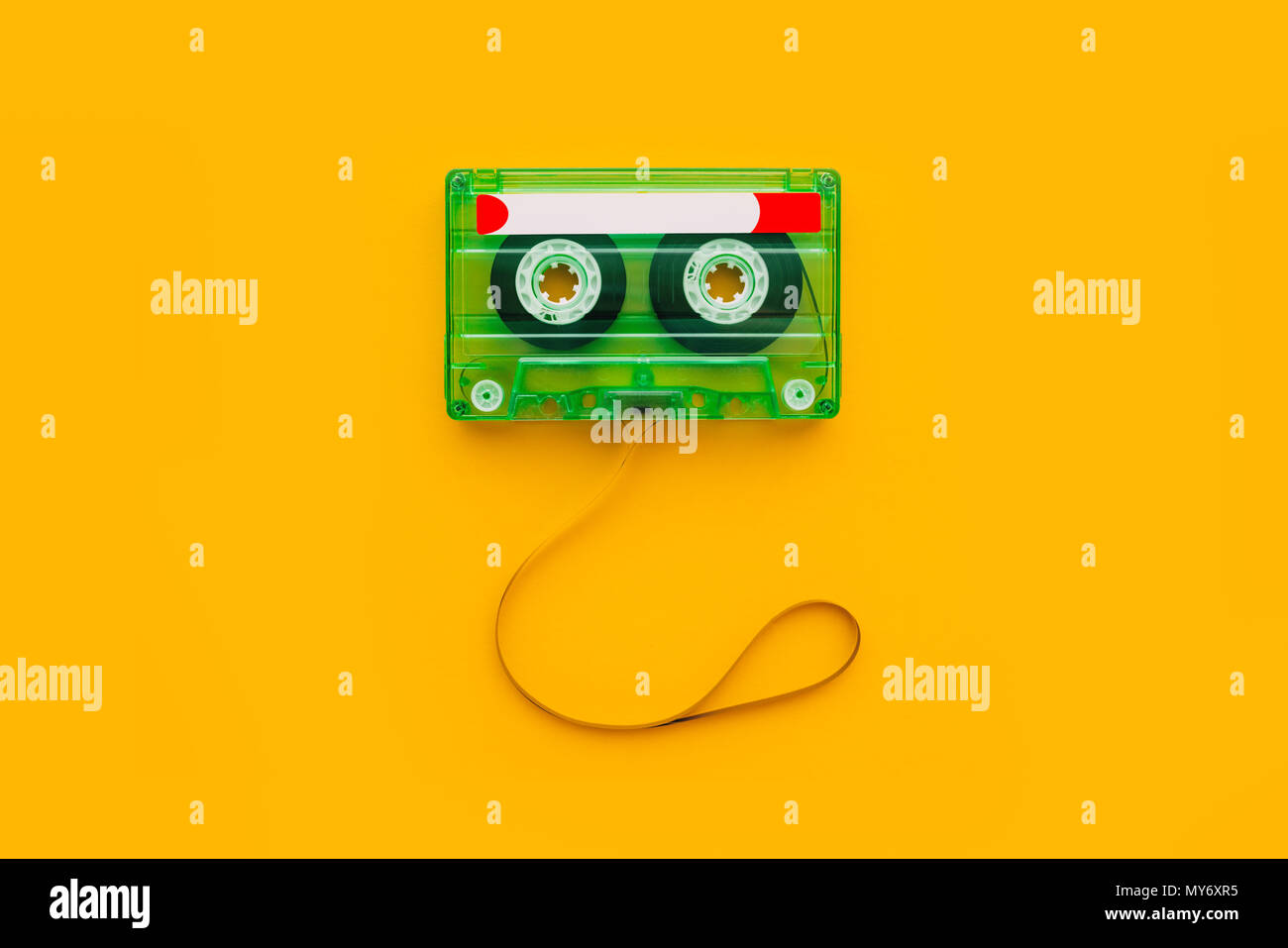 Top view of audio cassette with tangled tape on bright yellow