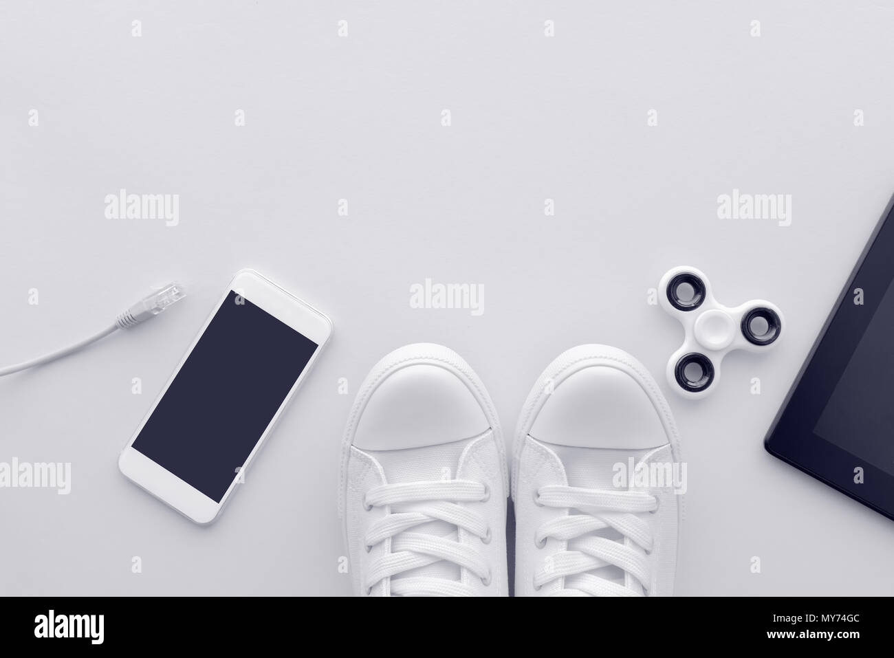 Millennial generation gadgets flat lay top view with copy space - minimalistic composition in pale white pastel tones including smartphone, computer n Stock Photo