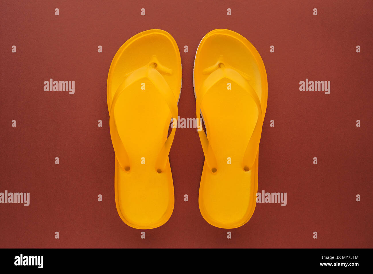 Yellow beach flip flops on brown background, top view Stock Photo