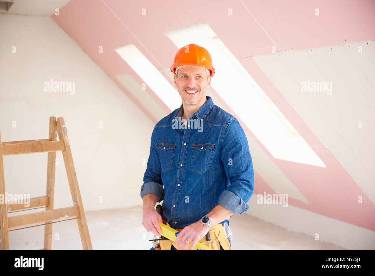 Confident middle aged handyman standing at construction site. Stock Photo
