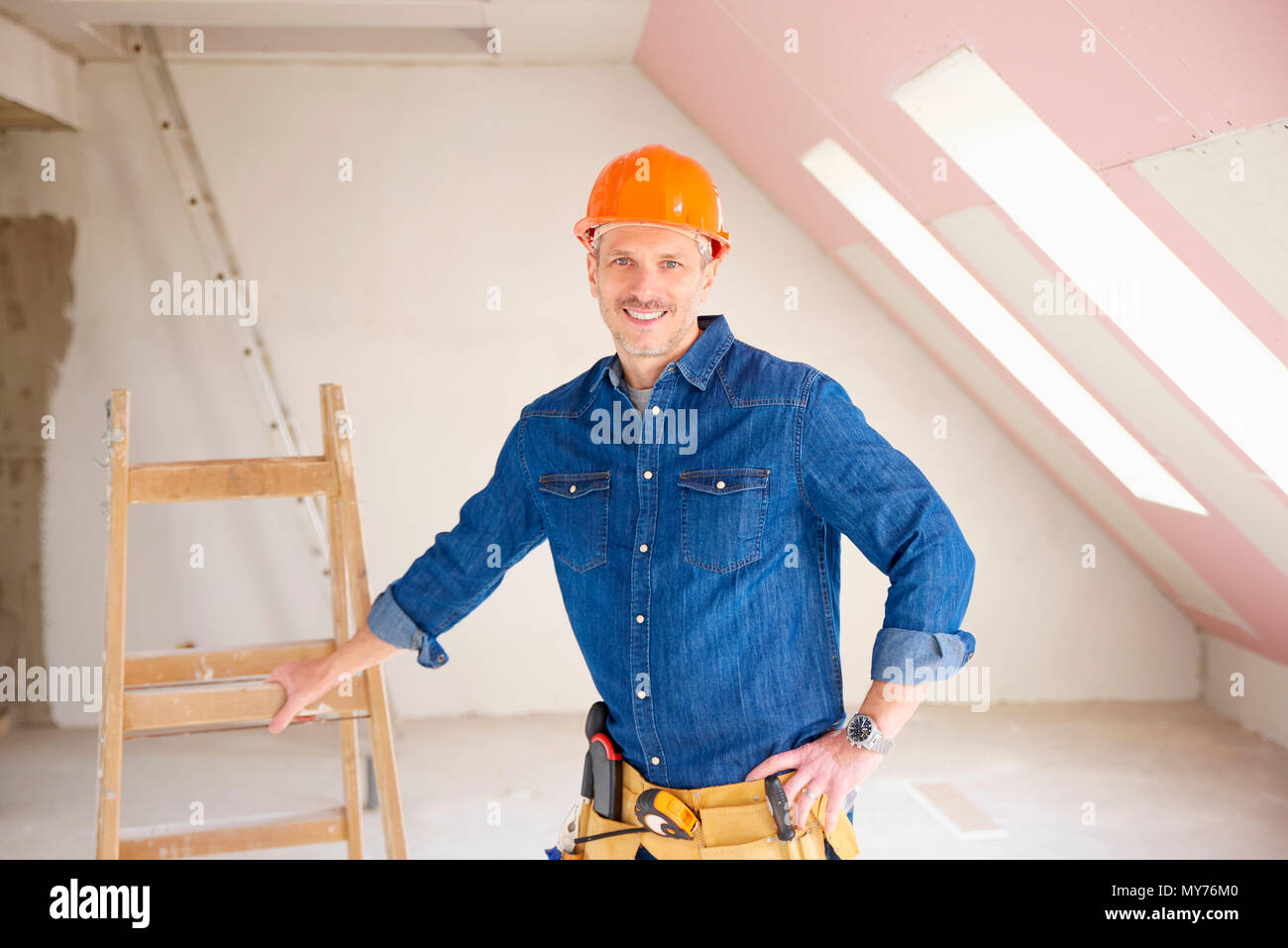 Confident middle aged handyman standing at construction site. Stock Photo