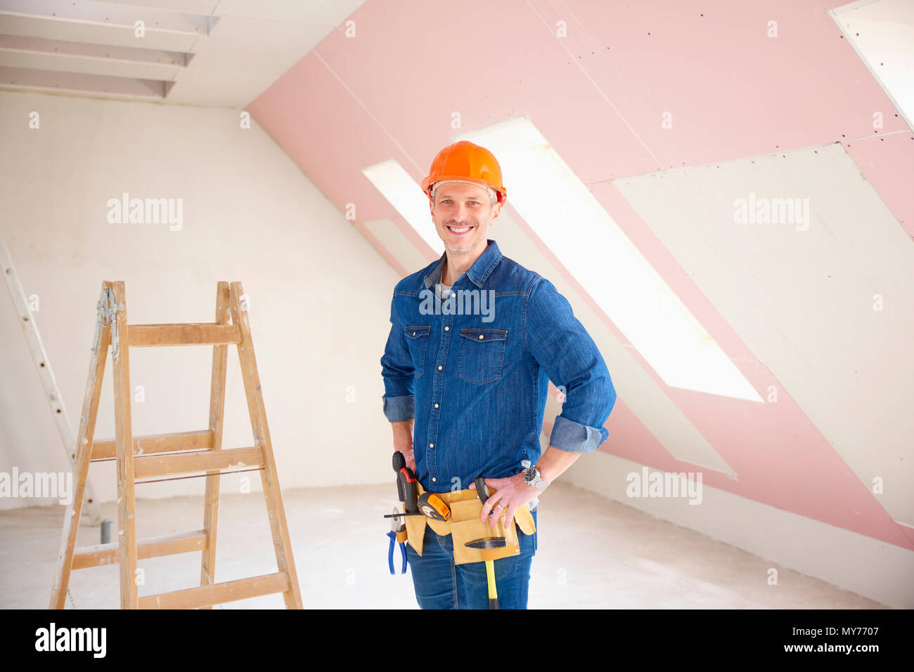 Confident middle aged handyman standing at construction site. Stock Photo