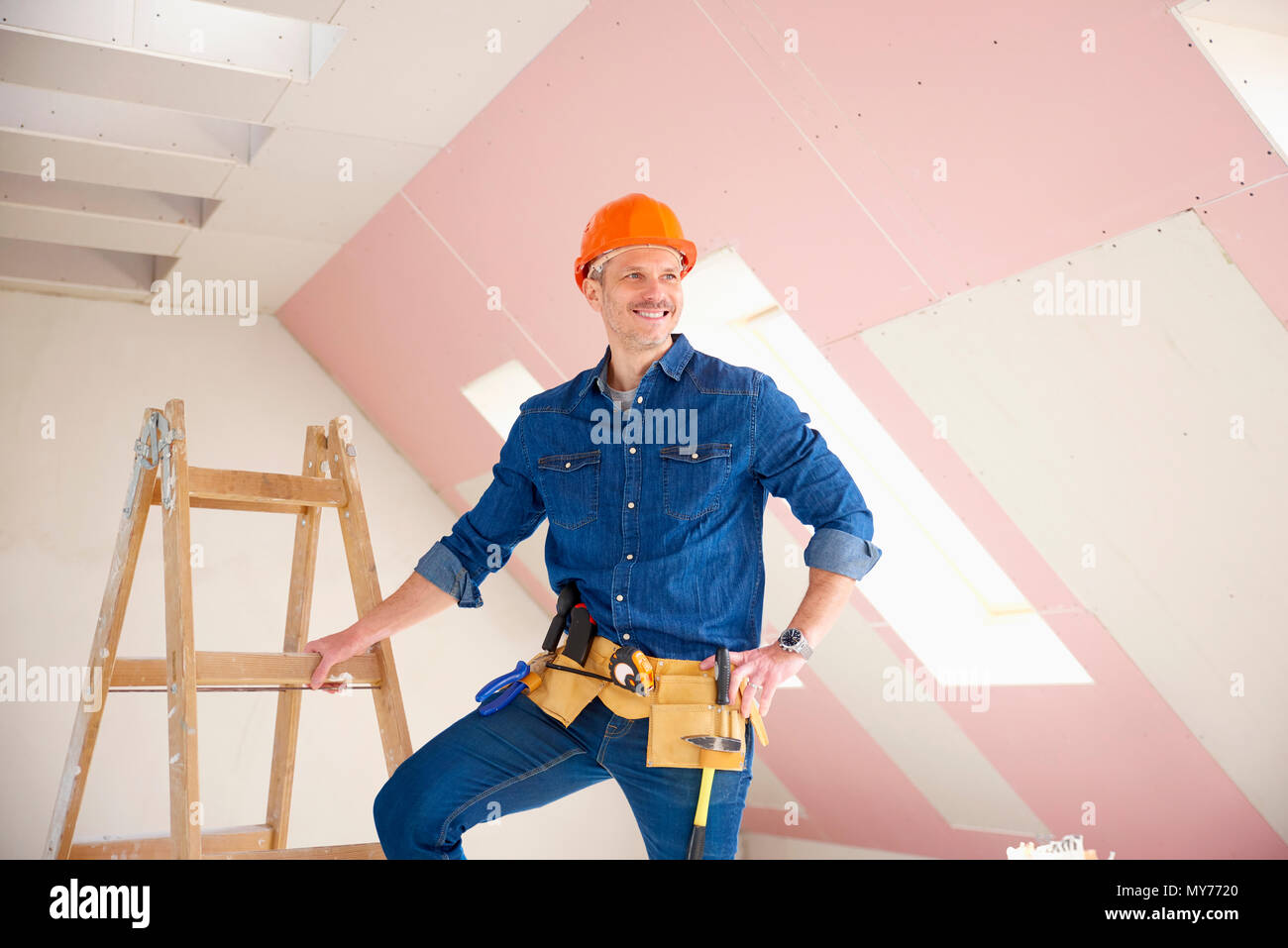 Confident middle aged handyman standing at construction site. Stock Photo