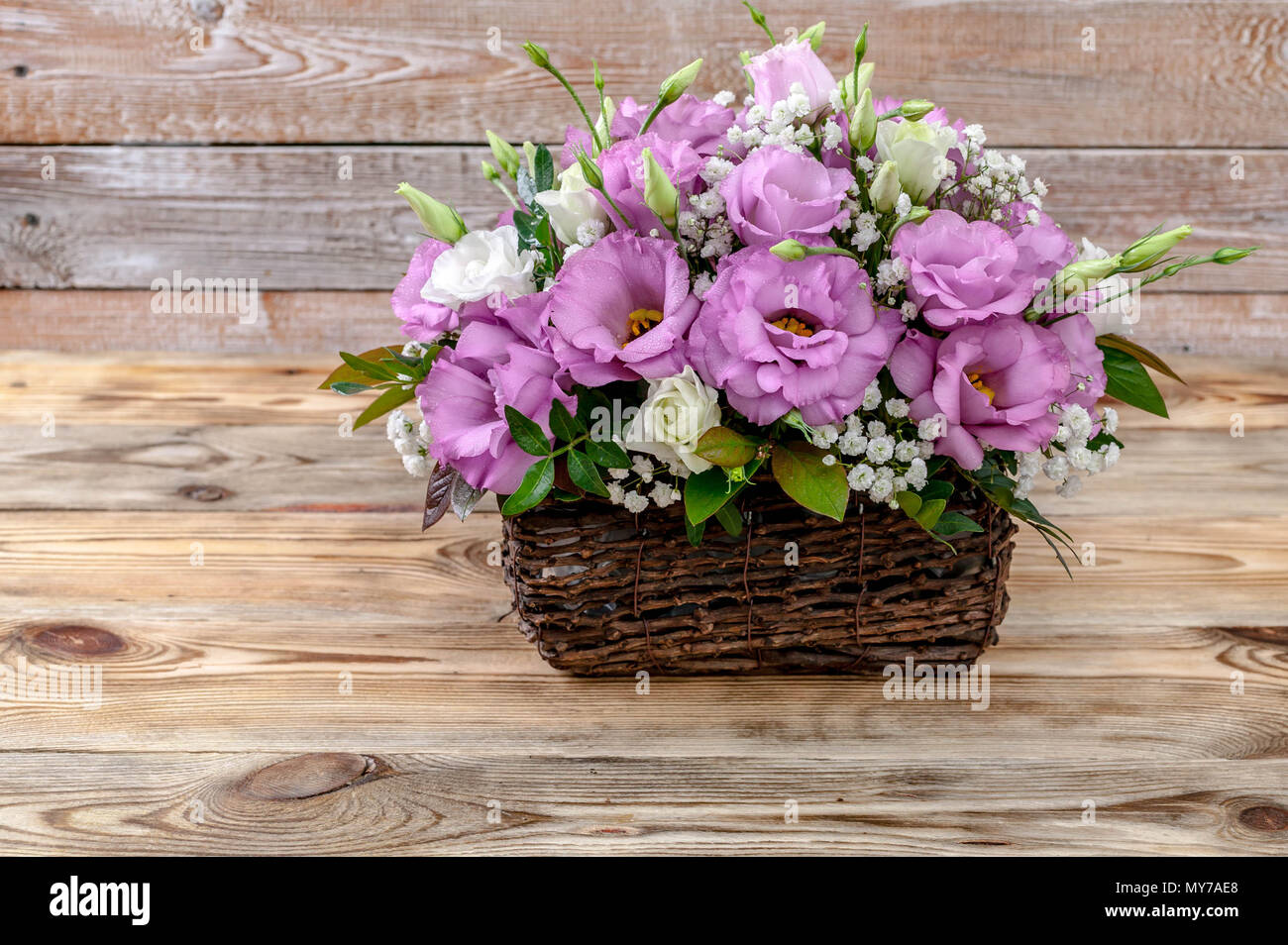 Bouquet of flowers in a basket on a wooden background. Stock Photo
