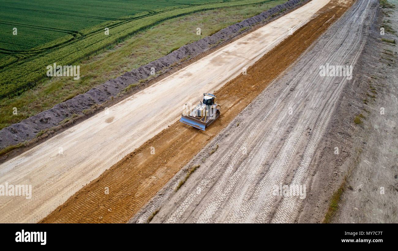 Aerial photo of a backhoe loader and a steamroller on a road work, France Stock Photo