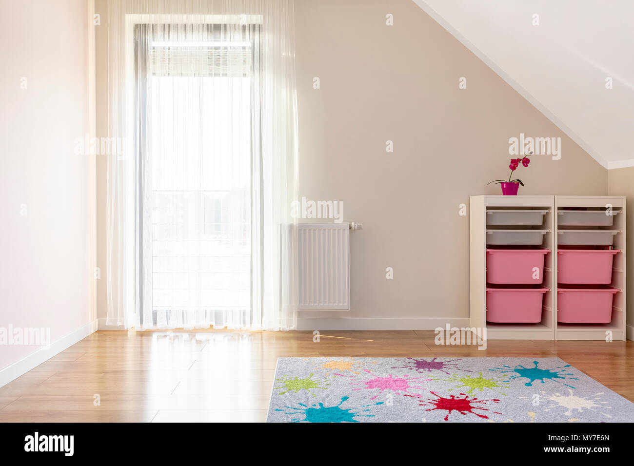 Patterned colorful carpet in kid's room interior with shelves and window. Real photo Stock Photo
