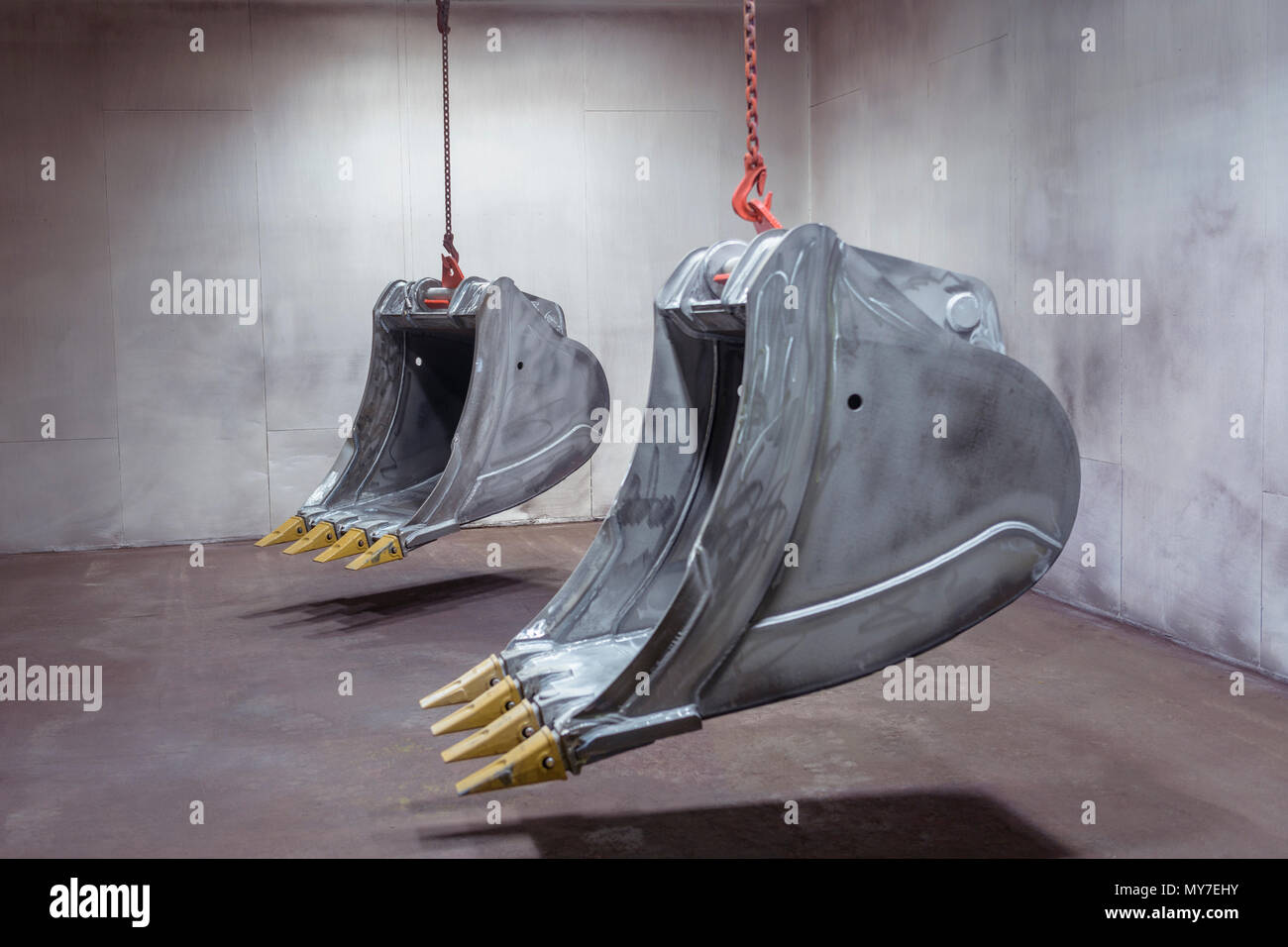 Digger buckets hanging in spray booth in engineering factory Stock Photo