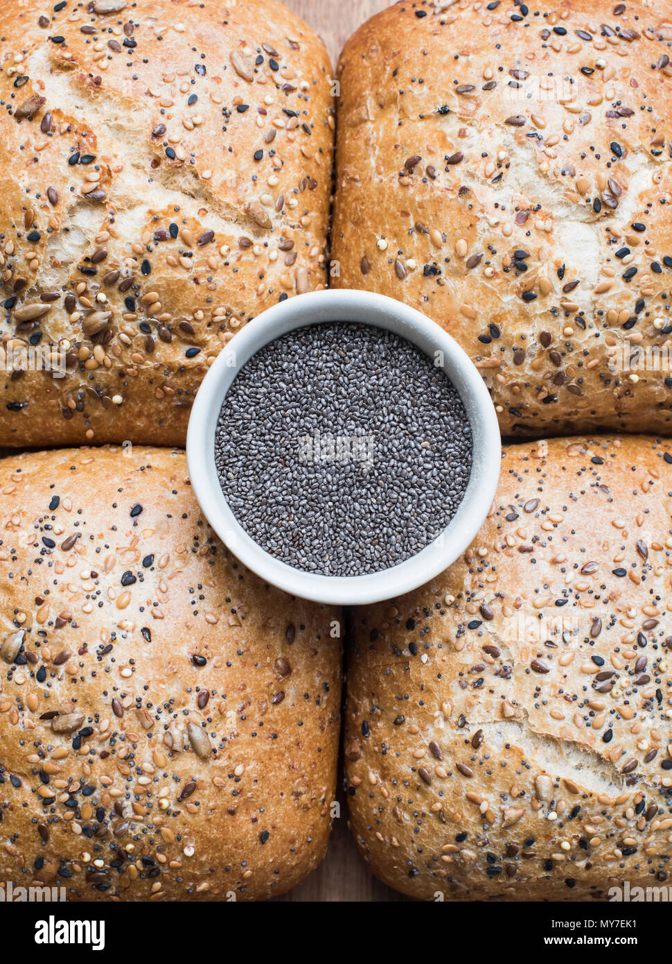 Multigrain bread rolls and bowl of chia seeds, close up overhead view Stock Photo